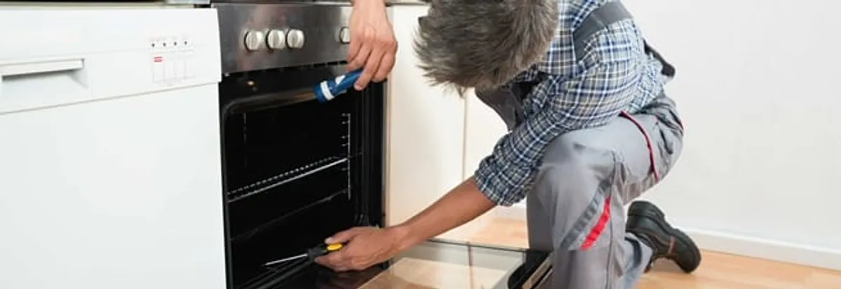 Oven repair technician inspecting and servicing an electric oven in Erie, PA