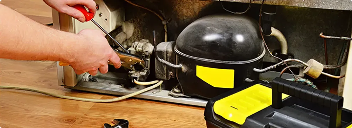 Refrigerator repair technician fixing the compressor and wiring in Erie, PA