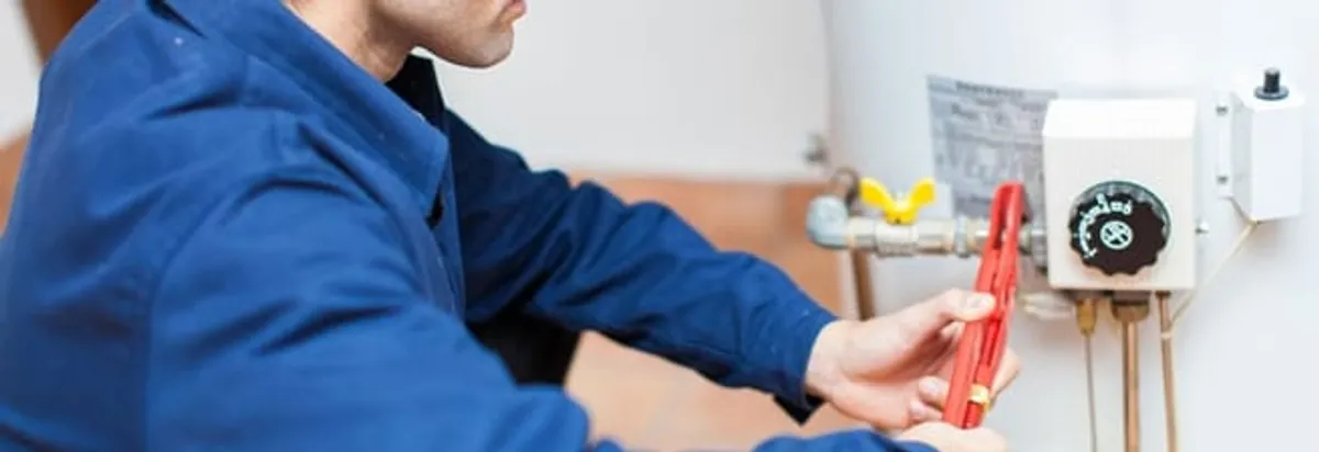 Water heater repair technician adjusting the temperature control and gas valve in Erie, PA